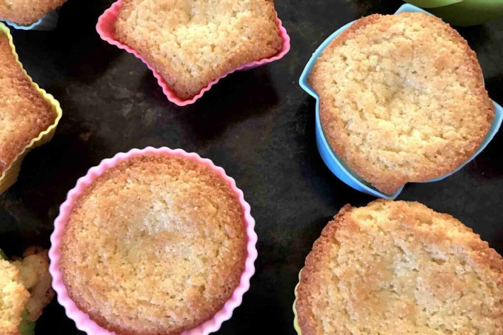 Close-up of several freshly baked muffins in colorful silicone baking cups on a dark background.