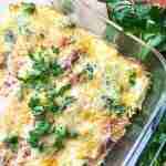Baked casserole topped with melted cheese and fresh parsley in a glass dish, with a bunch of parsley beside it.