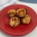 Macaroons on red plate with blurry background.