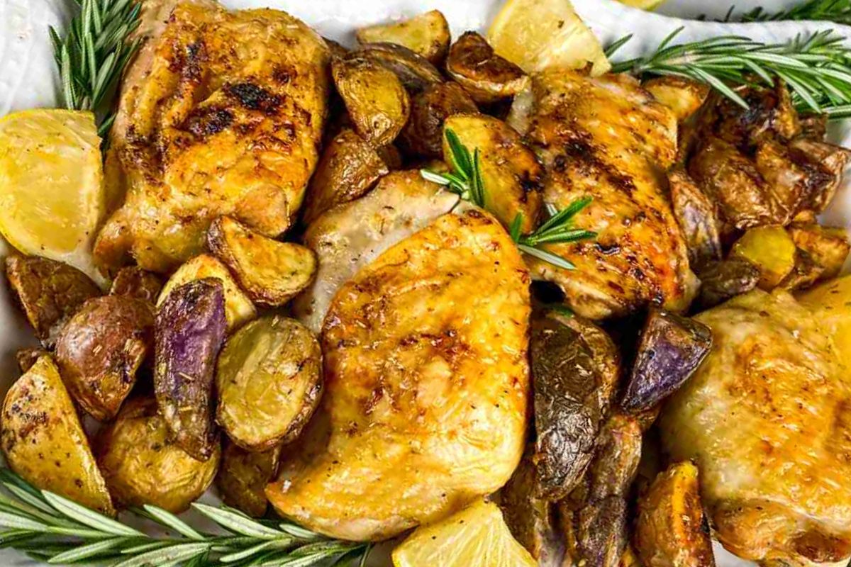 Grilled chicken thighs with various roasted potatoes and rosemary sprigs.