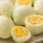 Peeled hard-boiled eggs seasoned with black pepper and salt on a plate.