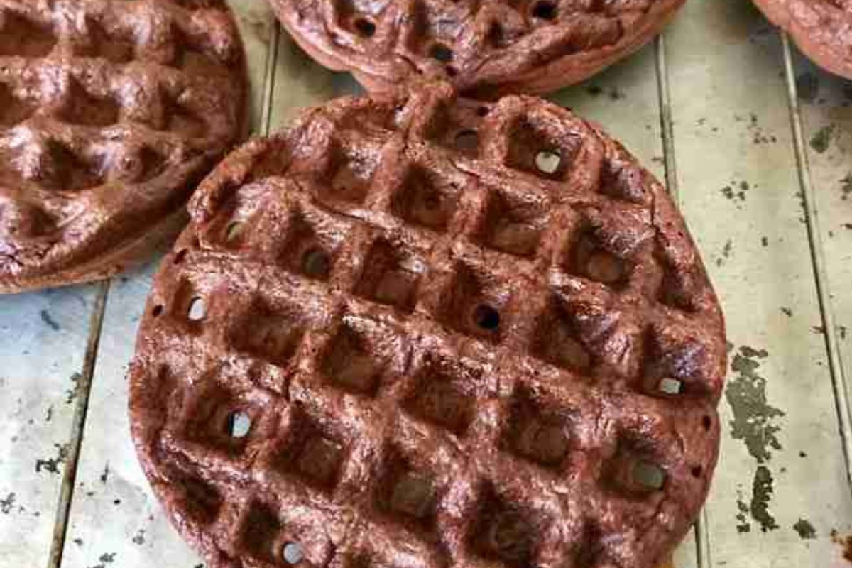 Several round chocolate waffles with grid patterns on a baking rack.