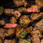 Cooked beef pieces infused with herbs, perfectly crisped as air fryer steak bites on a grill.