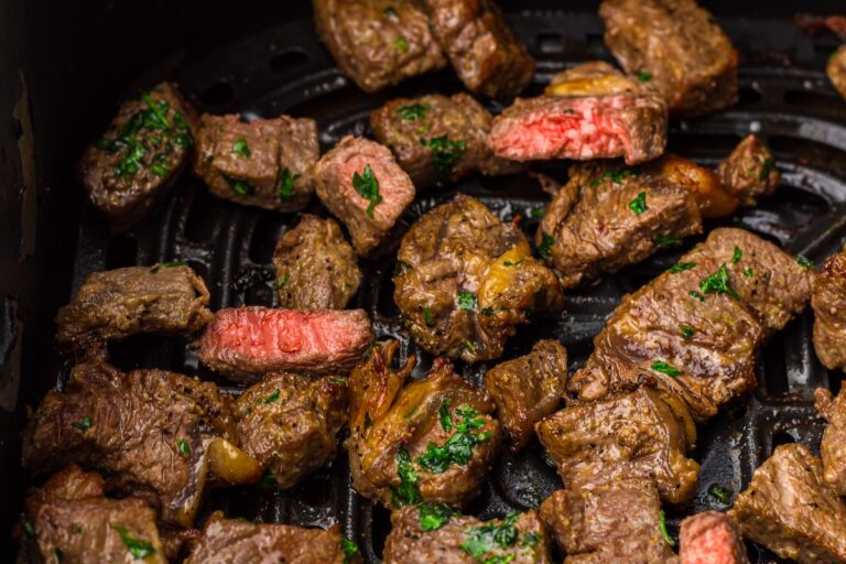 Cooked beef pieces infused with herbs, perfectly crisped as air fryer steak bites on a grill.