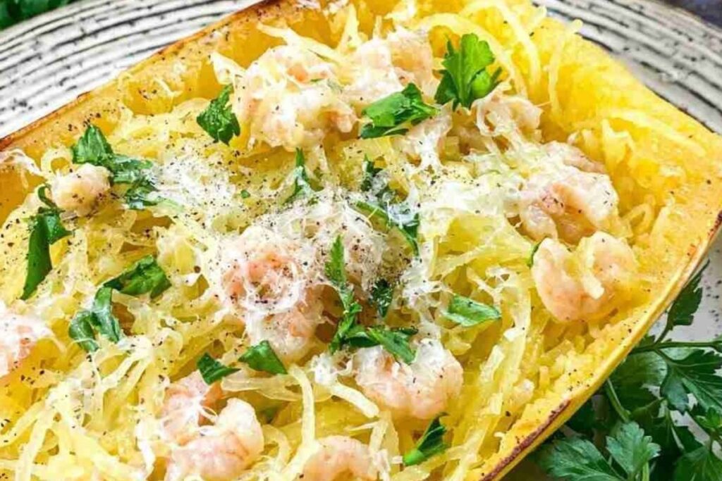 Spaghetti squash scampi filled with shrimp, topped with grated cheese and parsley, elegantly presented on a plate.