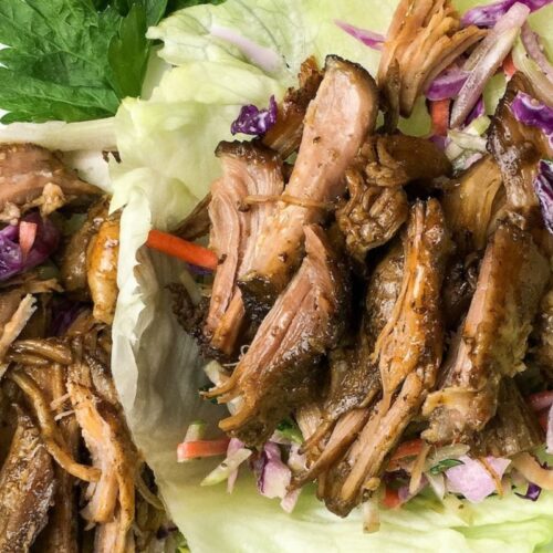 Pulled pork served in lettuce wraps with shredded purple cabbage and carrots.