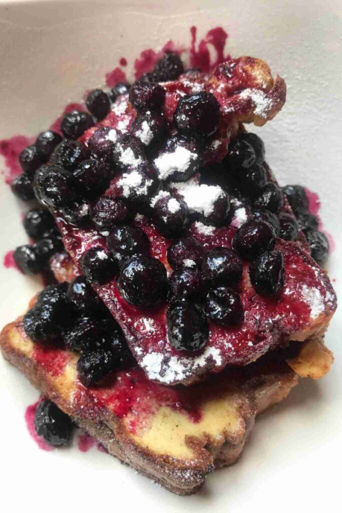 Stacked slices of French toast topped with a sugar-free blueberry compote and dusted with powdered sugar.