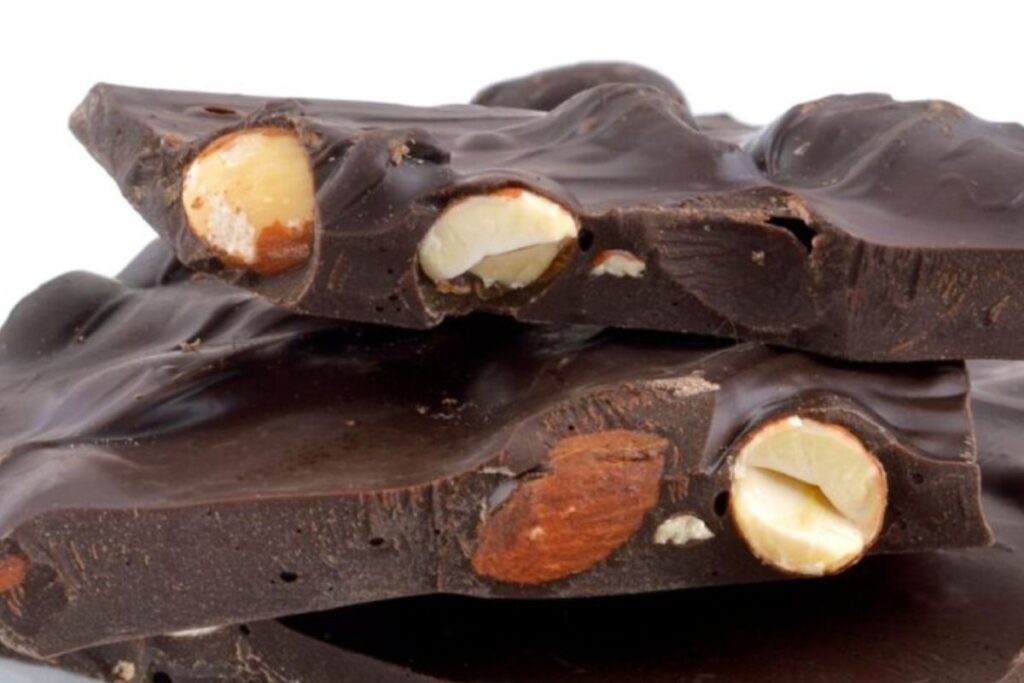 Close-up of dark chocolate pieces with whole almonds embedded inside.