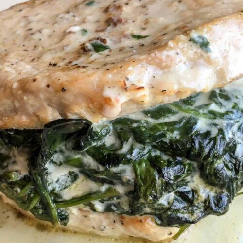 Stuffed pork chop with melted cheese and spinach filling on a plate.