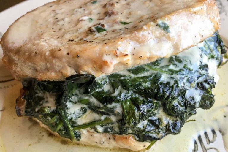 Stuffed pork chop with melted cheese and spinach filling on a plate.