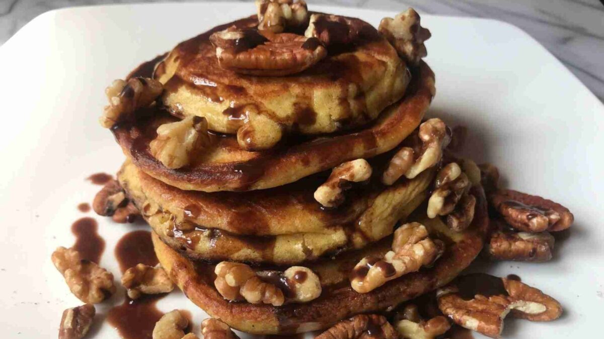 A stack of pancakes made with lupin flour topped with sugar-free syrup and nuts.