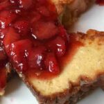 Close-up of meatless French toast slices topped with chunky strawberry sauce on a white plate.