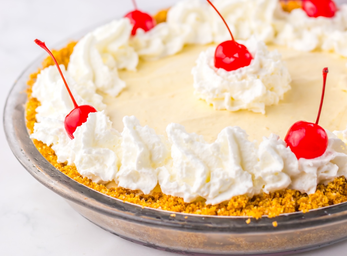 Cream pie with a crumb crust, topped with whipped cream and cherries.