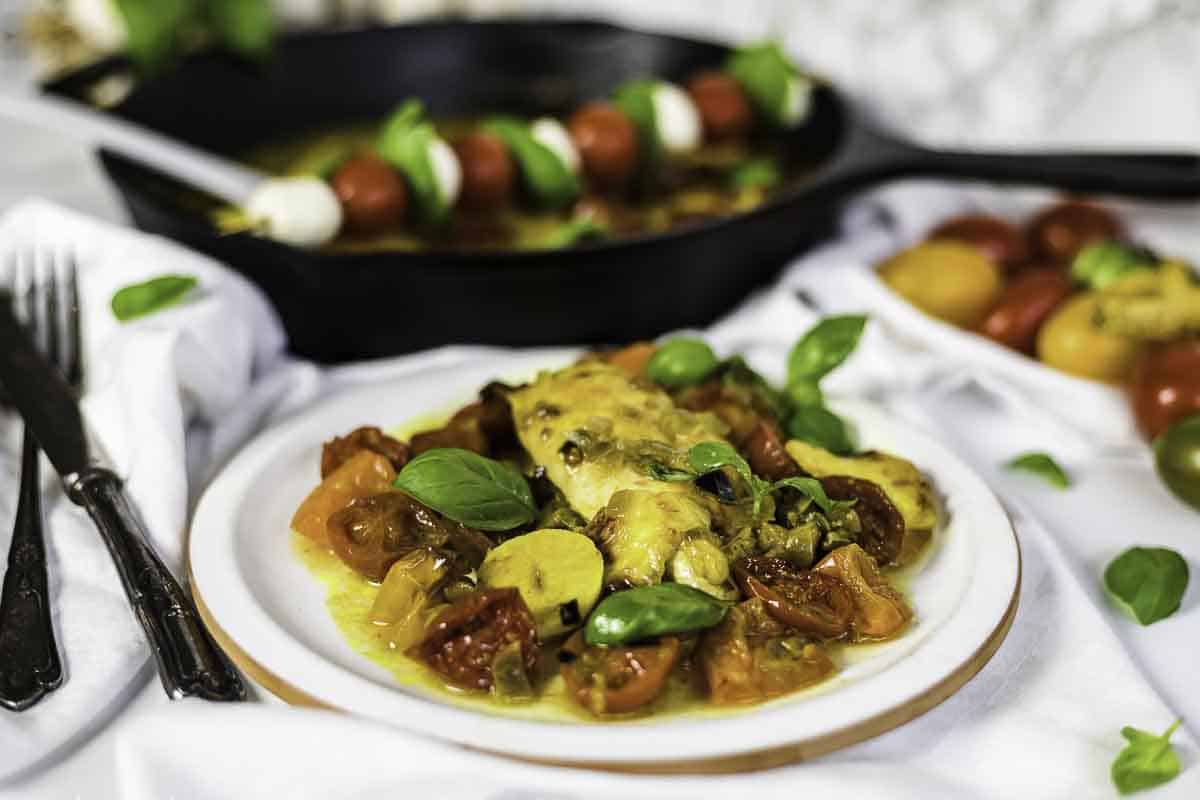 A plate of baked chicken breast with tomatoes, basil, and mozzarella.