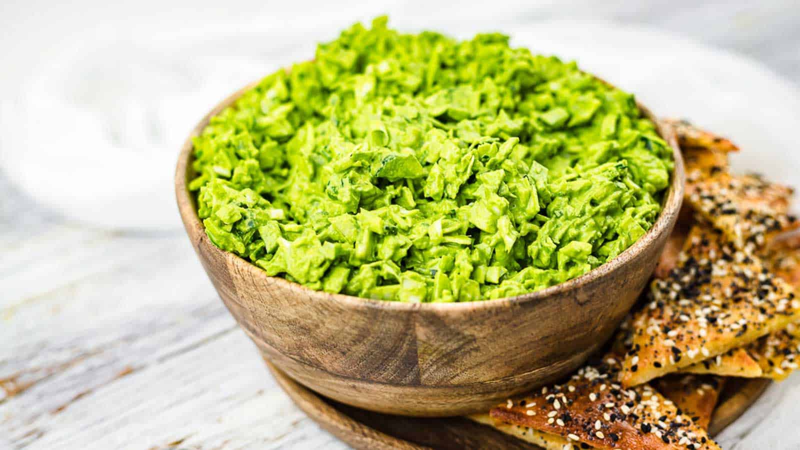 TikTok Green Goddess Salad inside a wooden bowl with crackers on the side.